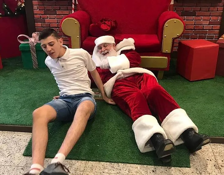 Papai Noel deita no chão para atender garoto autista e imagem viraliza nas redes