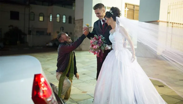 Morador de rua entrega flor para noivos e agradece o convite