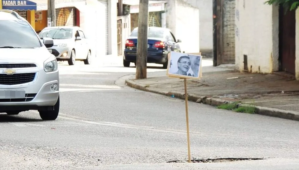 Moradores espalham placas com fotos do prefeito em buracos de rua