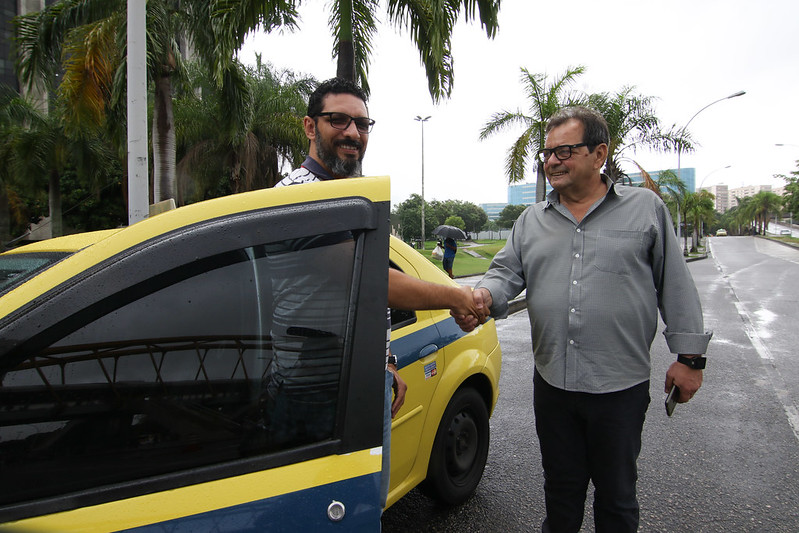 Motorista e passageiro contam as vantagens do aplicativo Taxi.Rio numa volta pela cidade