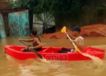Moradores usam caiaque para trafegar em ruas alagadas durante enchente em Itaguaí