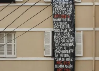 Mulher é fotografada nua pelos vizinhos e pendura faixa de protesto na janela