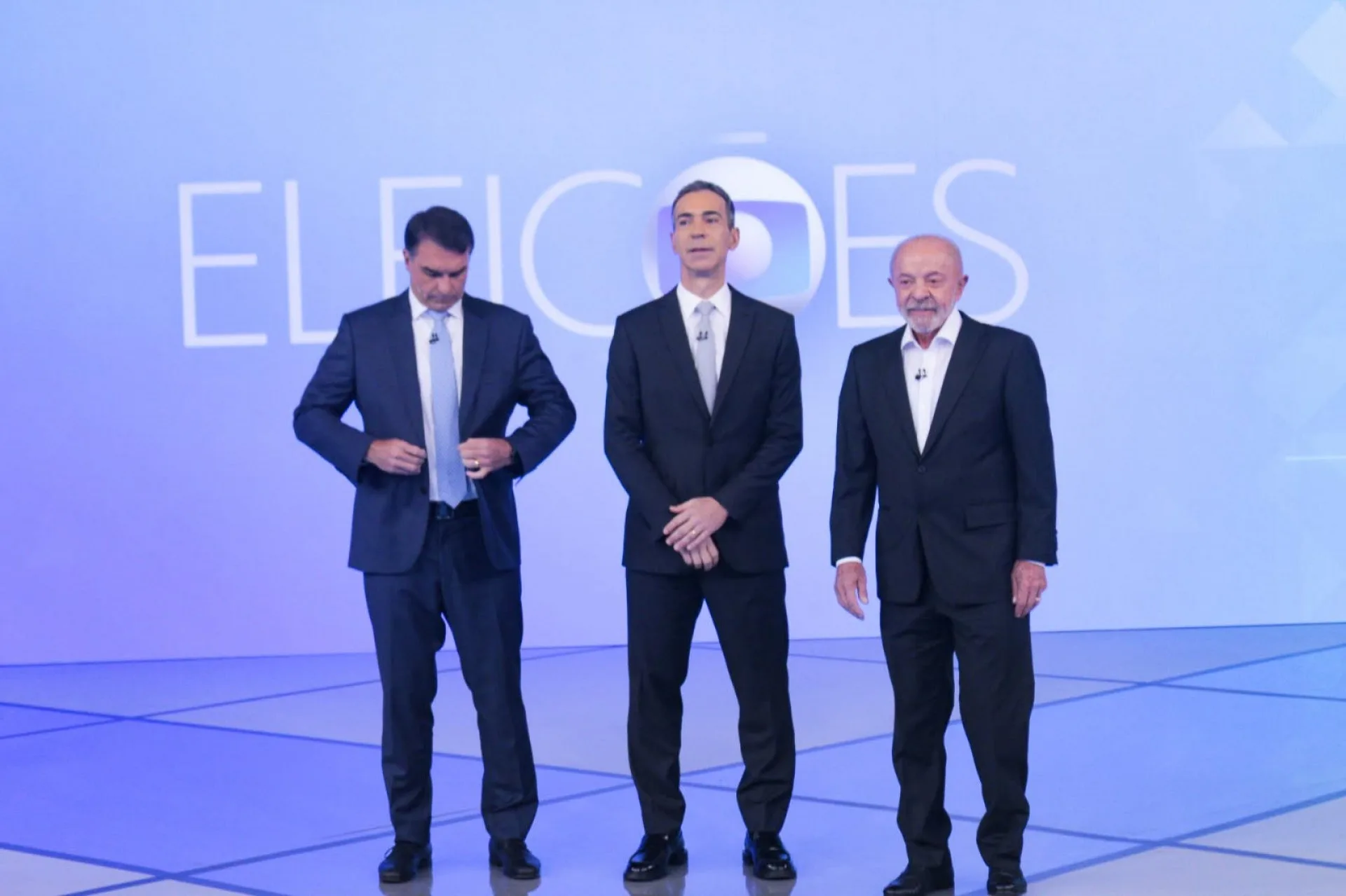 Flávio Bolsonaro (PL) e Lula (PT) ao lado do jornalista e mediador do debate César Tralli — Foto: Carlos Elias Junior/ Agência O Dia